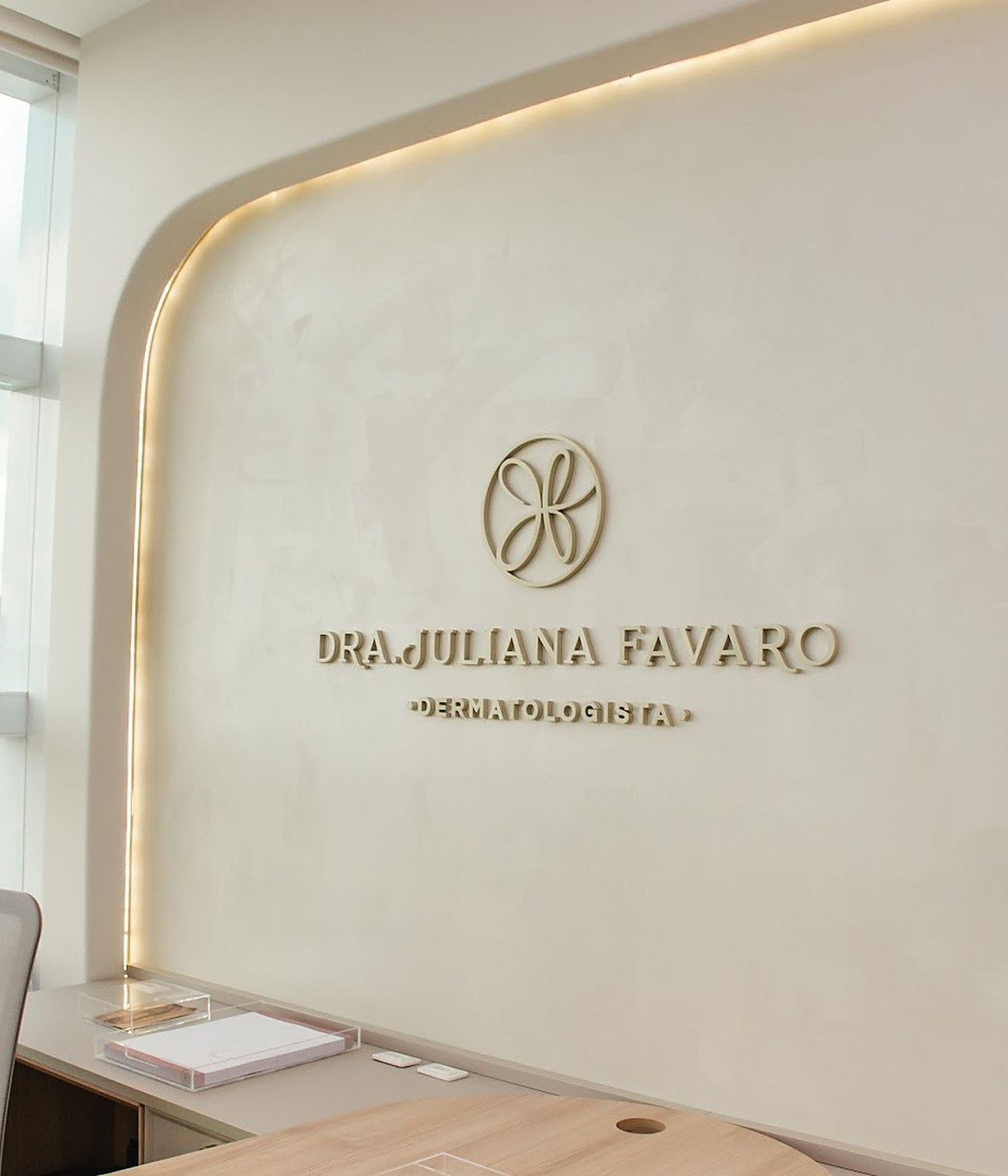 Parede do consultório da Dra. Juliana Favaro em Jundiaí, com o logotipo em relevo dourado